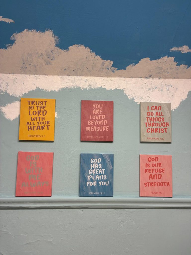 Six colourful Bible verse canvases on the sky painted wall, including Trust in the Lord with all your heart and God has great plans for you